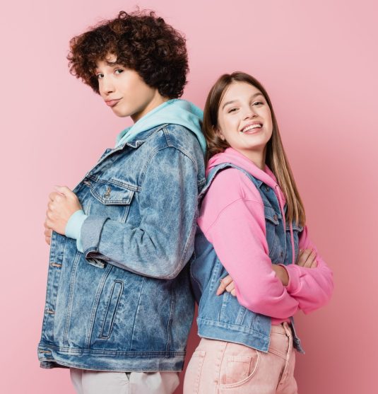 Teenagers in casual clothes looking at camera on pink background