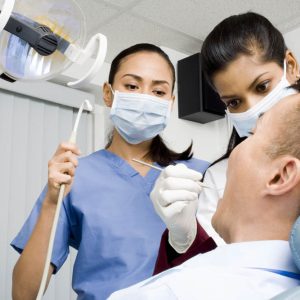 Dentist and dental hygienist performing procedure on patient